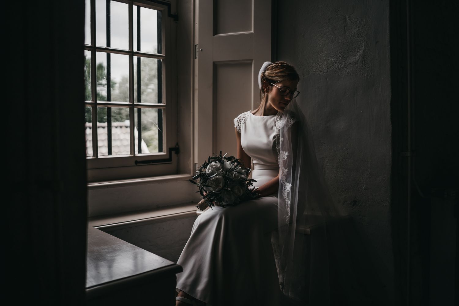 carola in trouwjurk bij raam